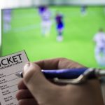 Men's hands with a ticket bookmaker's office, on TV show football, Champions League, sports betting, close-ups