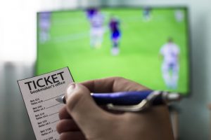 Men's hands with a ticket bookmaker's office, on TV show football, Champions League, sports betting, close-ups