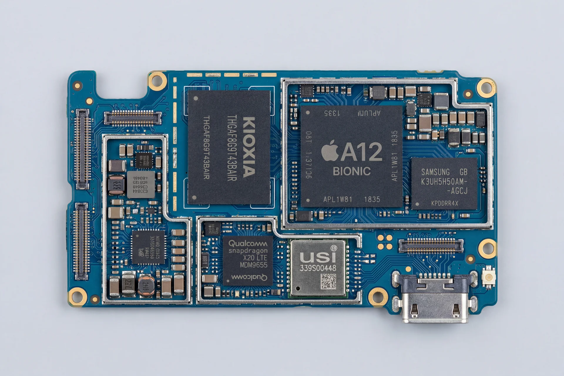 Carte mere iPhone A12 demontee : vue technique des composants avec connecteur USB-C
