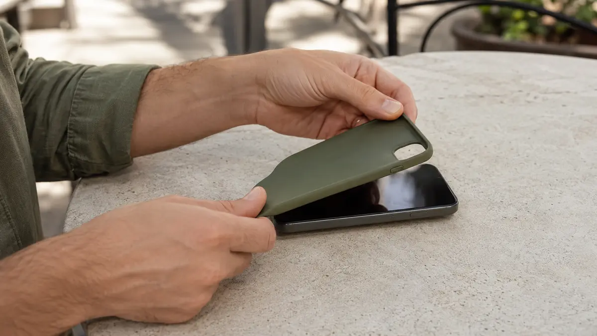 Personne retirant la coque d’un smartphone chaud posé à l’ombre